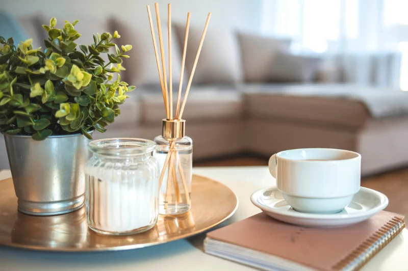 Items decorating a table include coffee cup, room fragrance sticks, and candle